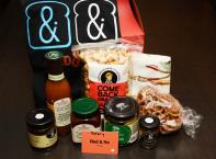 Gift box filled with Red&Ko gift card, t-shirt size large, tea towel, Come Back Snacks double coated caramel popcorn, seasoned pretzels, Curried mango grille sauce, spicy chili bacon jam, jalepino stuffed olives, cranberry port mustard, and apple rum chutney.